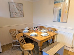Un comedor con una mesa de madera dispuesta para cuatro personas, rodeada de sillas de madera.