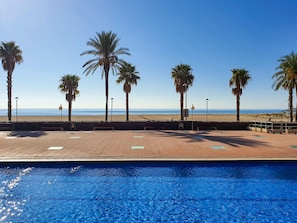 Una piscina con vista a la playa y palmeras.