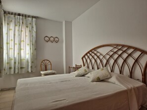 Een slaapkamer met een bed, een stoel en een wandplank.