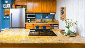 A kitchen with wooden cabinets, a stainless steel refrigerator, a microwave, and a sink. - Oceanfront Hauula 1BR Condo I Beach, Pool, Parking (Hauula)