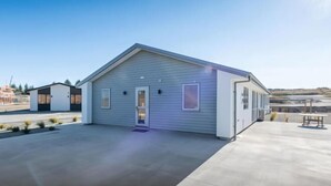 A modern building with a flat roof, a central entrance, and a covered outdoor area with a table and chairs. - 18 Jimmy (Lake Tekapo)