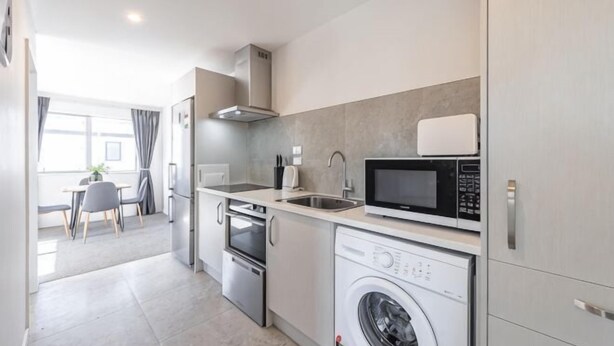 A compact kitchen with a microwave, oven, and washing machine. - 18 Jimmy (Lake Tekapo)