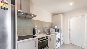 A compact kitchen with a refrigerator, microwave, oven, and washing machine. - 18 Jimmy (Lake Tekapo)