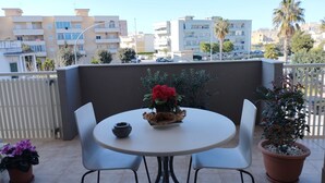 Un balcon avec une table ronde, deux chaises, un pot de fleurs et un petit bol.