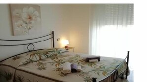 Un lit avec une couvre-lit à motifs floraux, une lampe de chevet et un tableau accroché au mur.