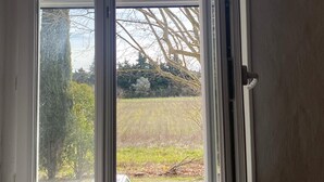Una habitación con un ventanal grande, una puerta blanca y vistas a árboles y un campo.