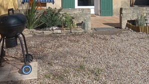 Una casa de dos pisos con contraventanas verdes, una parrilla y un camino de entrada de grava.