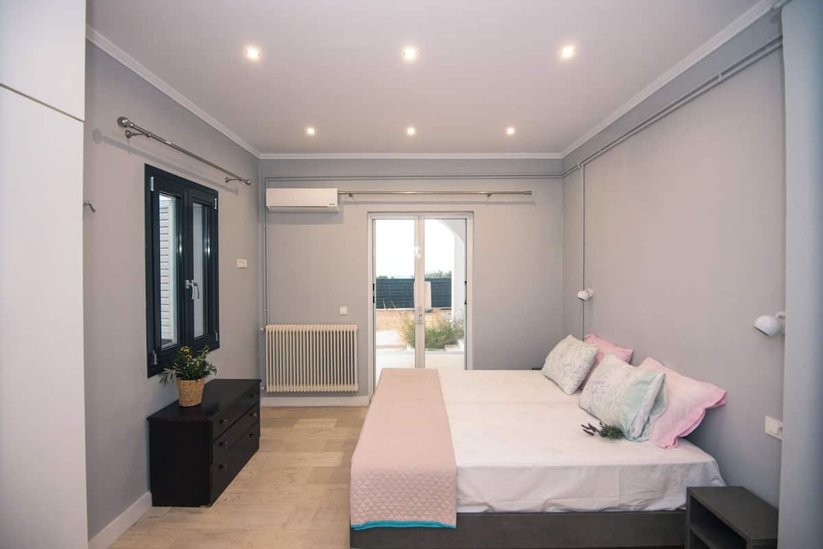 A bedroom with a bed, a dresser, a radiator, and a window.