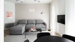 A modern living room with a grey sectional sofa, a black coffee table, and a floor lamp. - Chic 2 Keren Hayesod (Jerusalem)