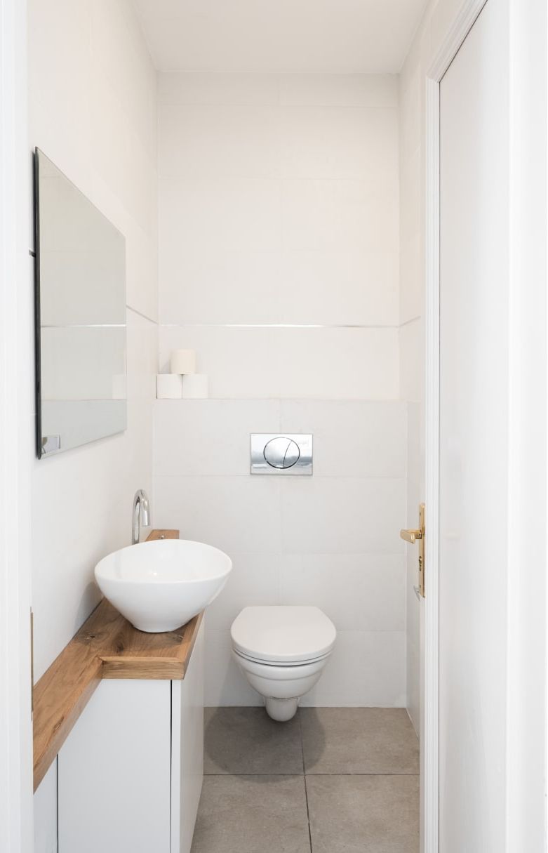 A small, modern bathroom with a white sink, toilet, and mirror.