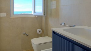 A bathroom with a toilet, bidet, and a window with a view of the sea. - IRIS Aurora Apartments (Baia Azzurra-levagnole)