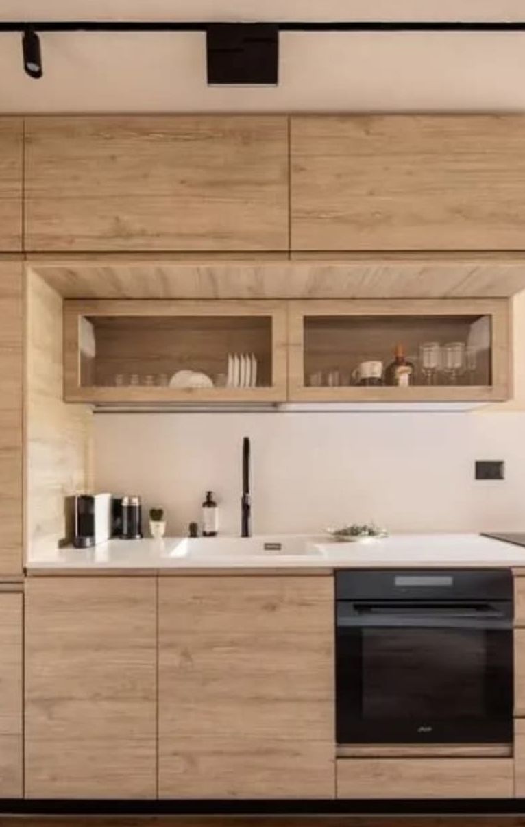 A modern kitchen with wooden cabinetry, a built-in dishwasher, and a countertop with various kitchen items.