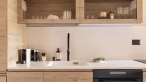 A modern kitchen with wooden cabinets, a built-in dishwasher, and a glass-fronted upper cabinet. - Luxury Mamilla view - Three Bedroom Apartment, Sleeps 8 (Jerusalem)