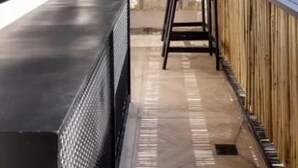 A balcony with a stone wall, a black chair, and a wooden table. - Luxury Mamilla view - Three Bedroom Apartment, Sleeps 8 (Jerusalem)