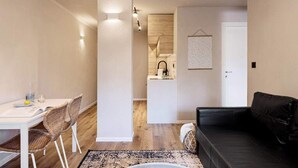 A compact living space with a dining area, a black sofa, and a kitchenette. - Luxury Mamilla view - Three Bedroom Apartment, Sleeps 8 (Jerusalem)