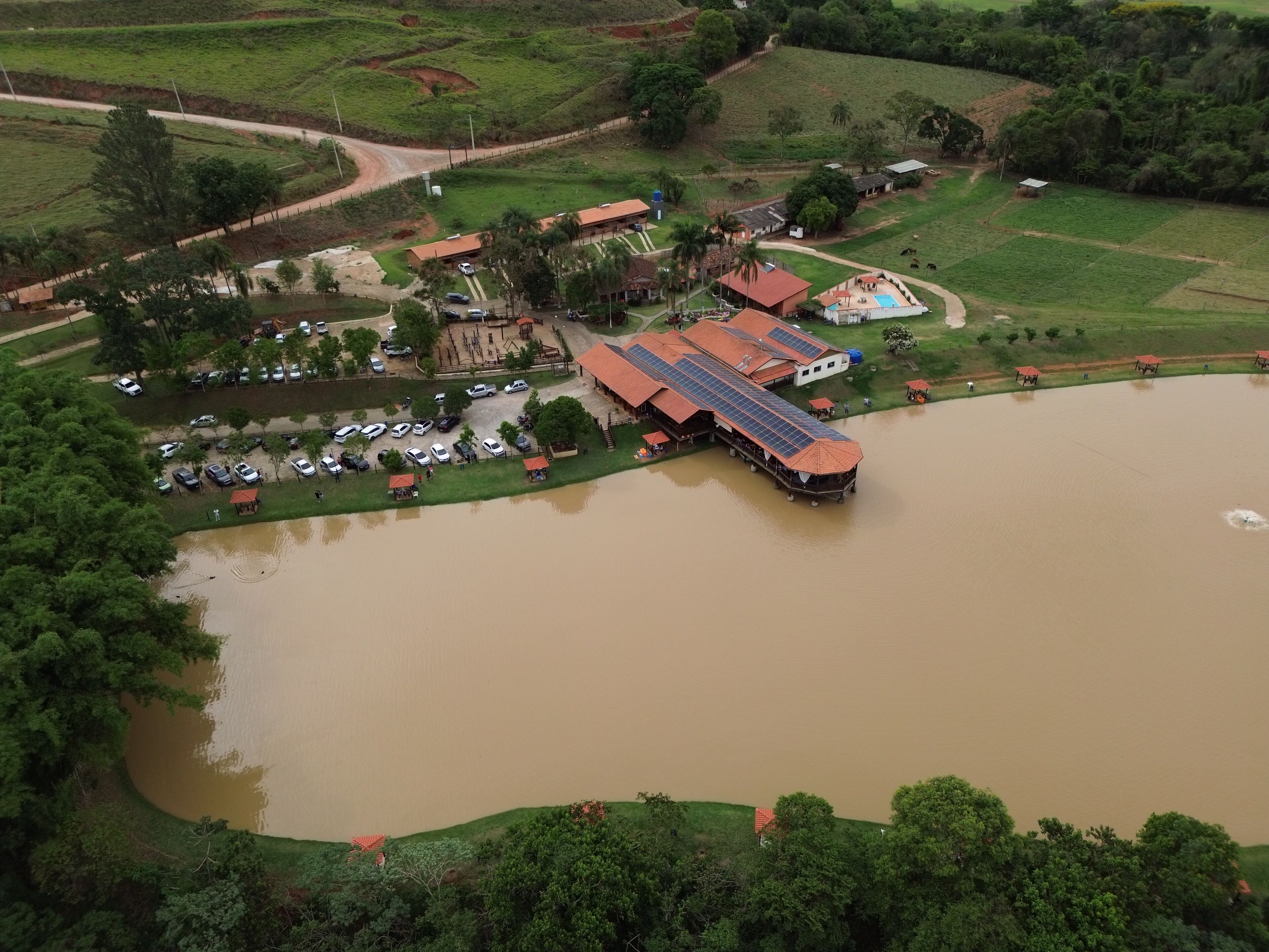 Vista aérea de um resort com um edifício grande, piscina e um corpo de água.