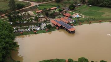 Vista aérea de um resort com um edifício grande, piscina e um corpo de água.