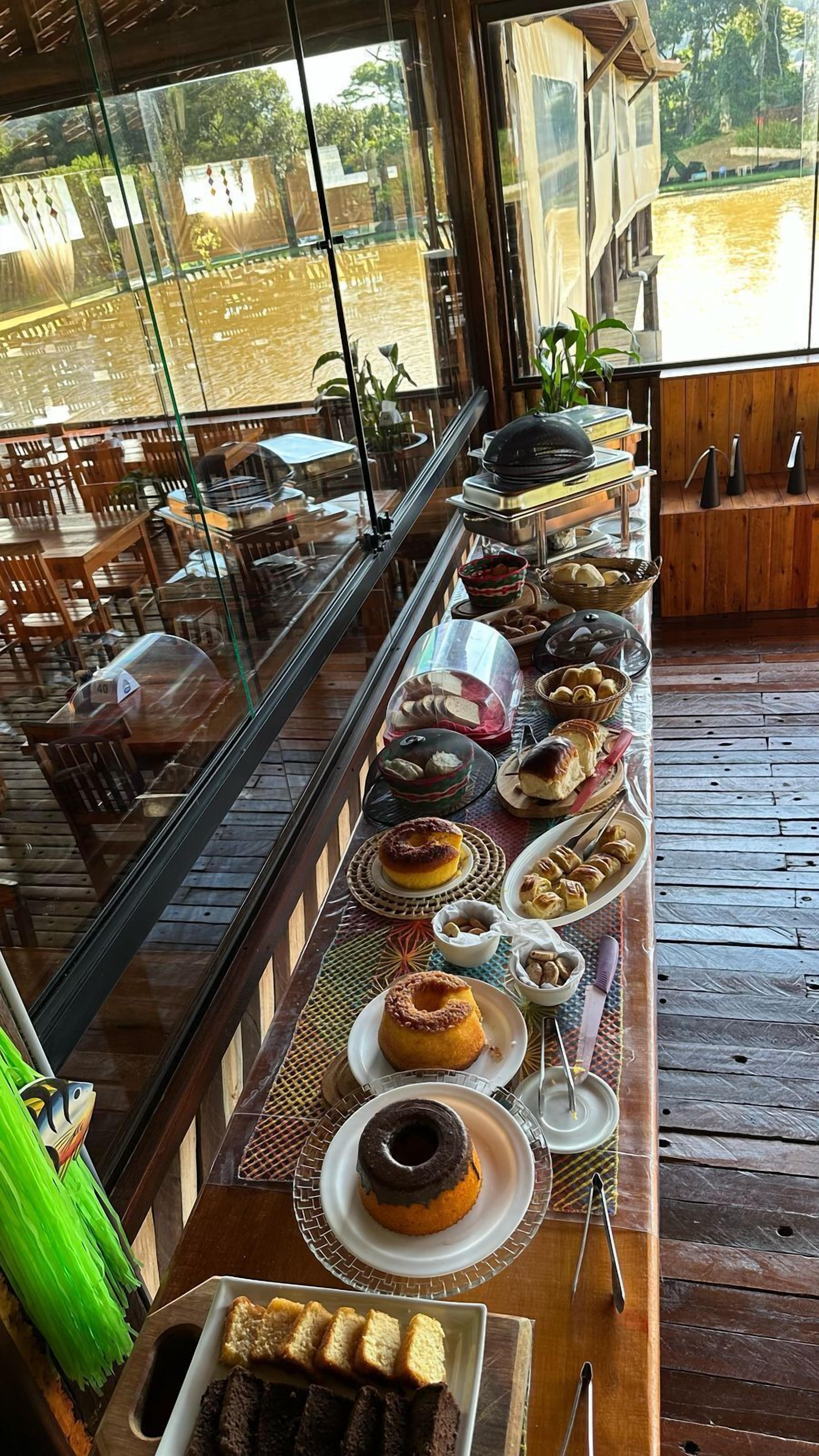 A buffet table with various food items and a view of the outdoors through large windows.