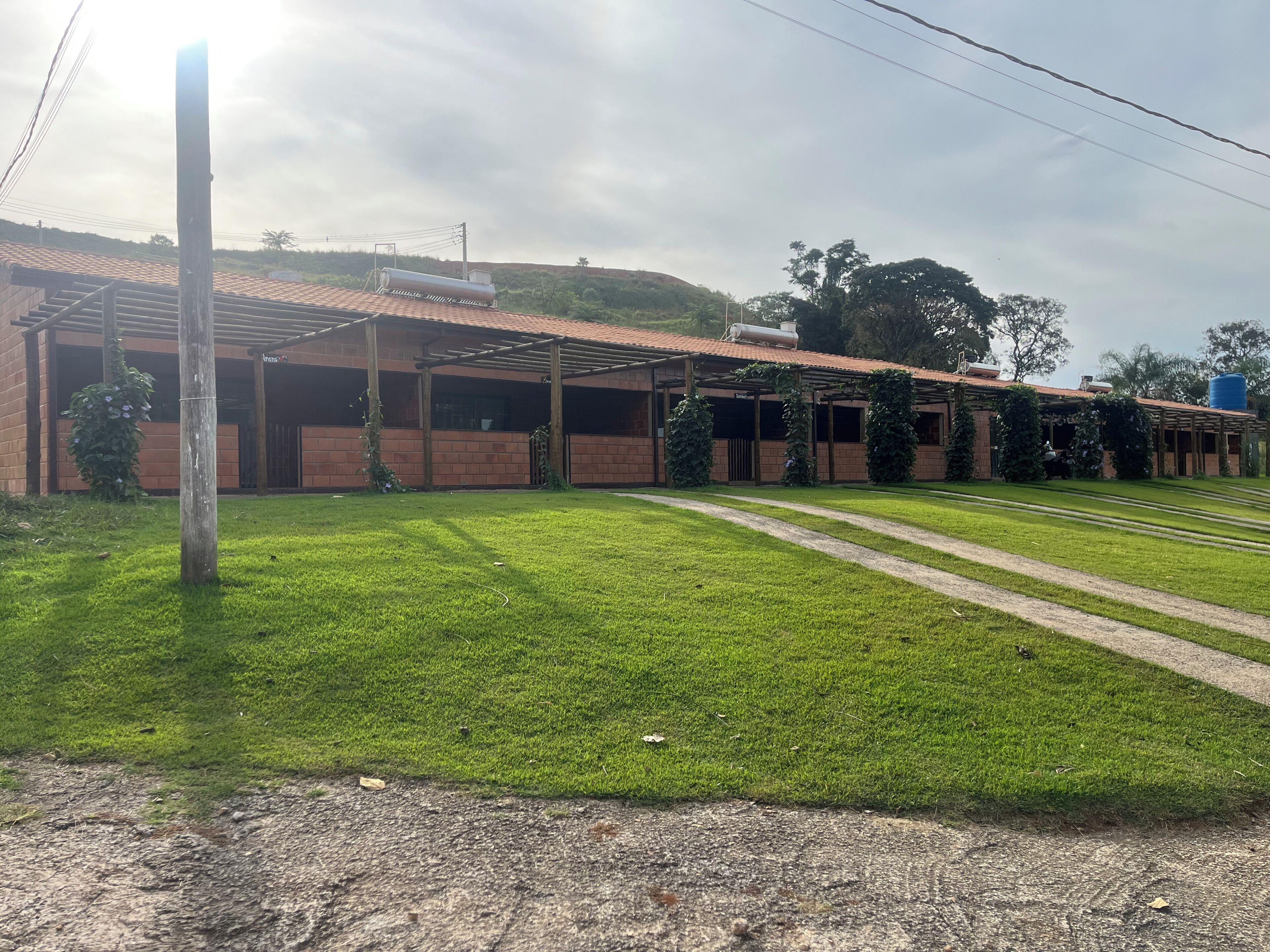 Un edificio con un patio cubierto, un césped y un depósito de agua al fondo.