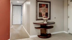 Un couloir avec une table ronde et une œuvre d’art encadrée accrochée au mur.