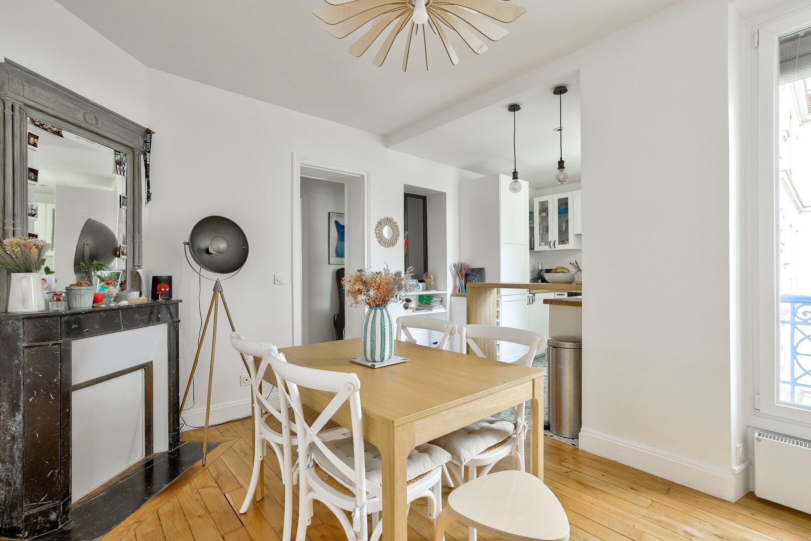 A modern kitchen with white cabinets, a wooden dining table, and white chairs.