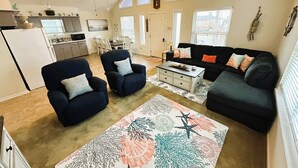 A living room with a dark blue sofa, two armchairs, a coffee table, and a patterned rug. - Fishing Haven at Linda's Mermaid Cove (Freeport)