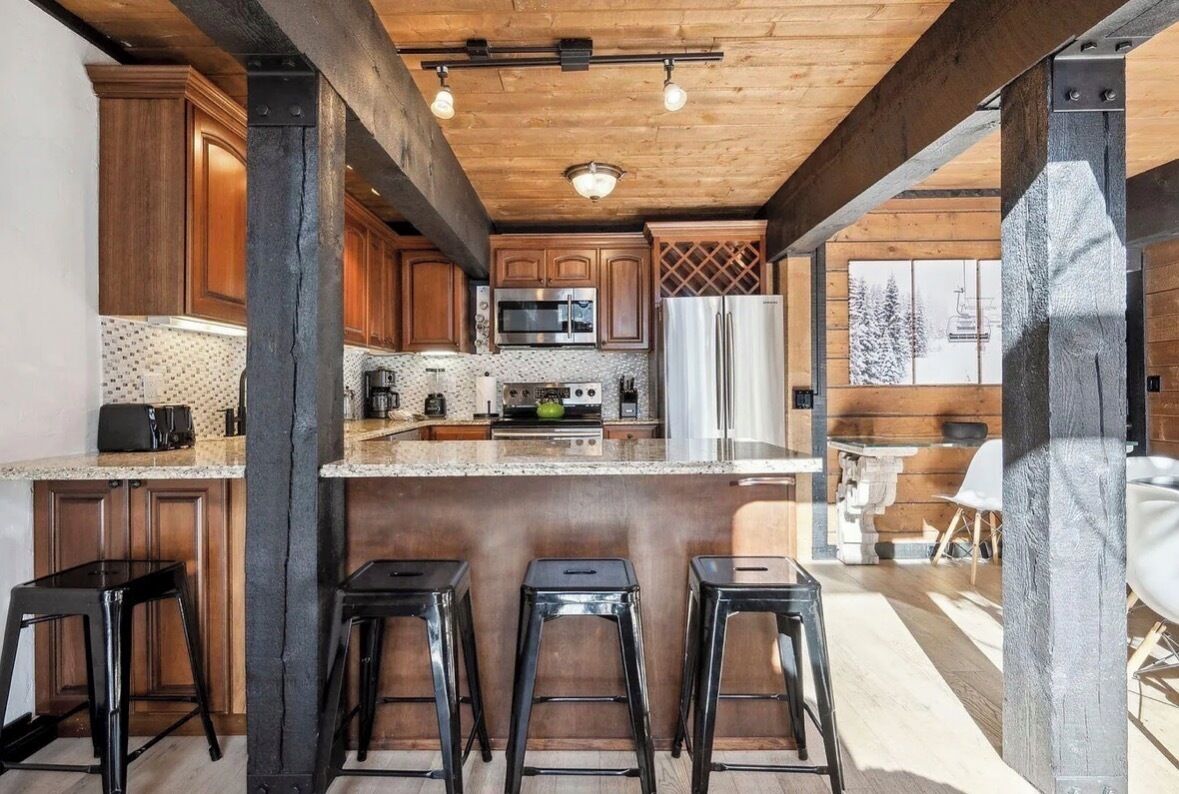 A kitchen with wooden cabinets, a stainless steel refrigerator, and a central island with stools.