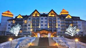 A multi-story hotel with a symmetrical facade, multiple balconies, and a central entrance with steps leading up to it. - InterContinental ALPENSIA PYEONGCHANG RESORT by IHG (Pyeongchang-gun)