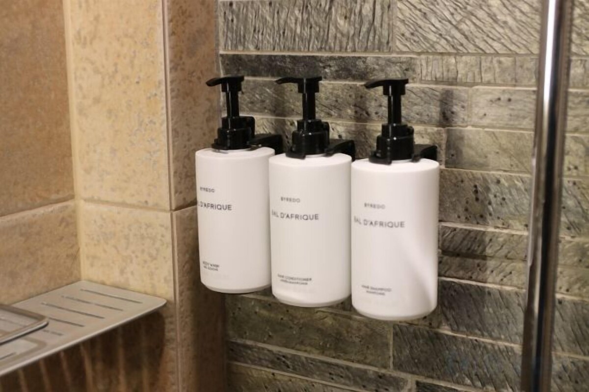 Three white bottles with black pumps on a tiled wall.