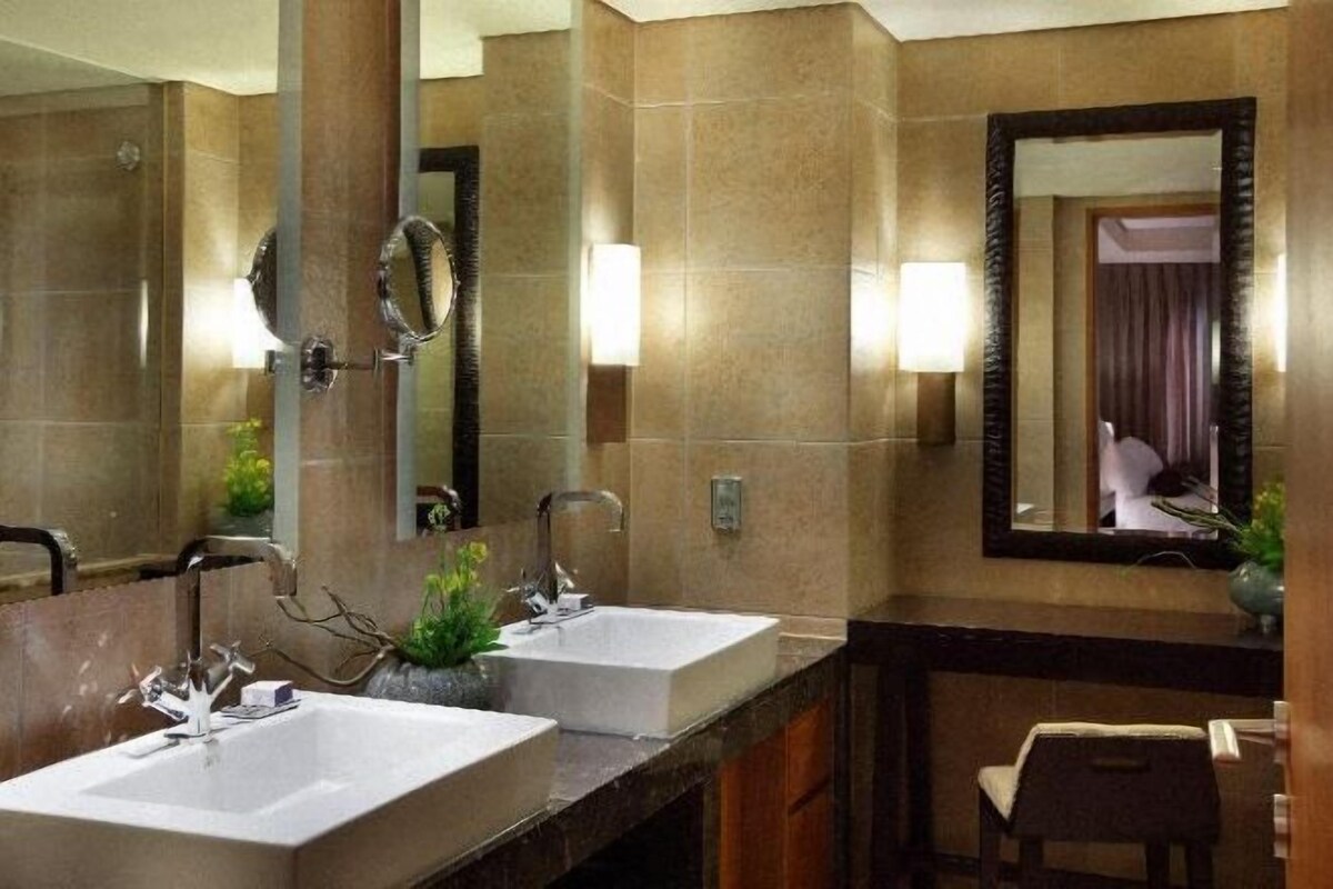 A bathroom with two sinks, a mirror, and a chair.