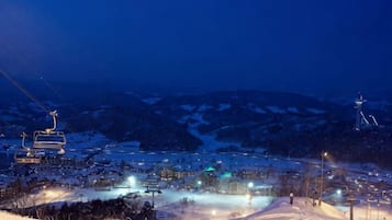 Un poble cobert de neu amb un remuntador d'esquí i edificis il·luminats.
