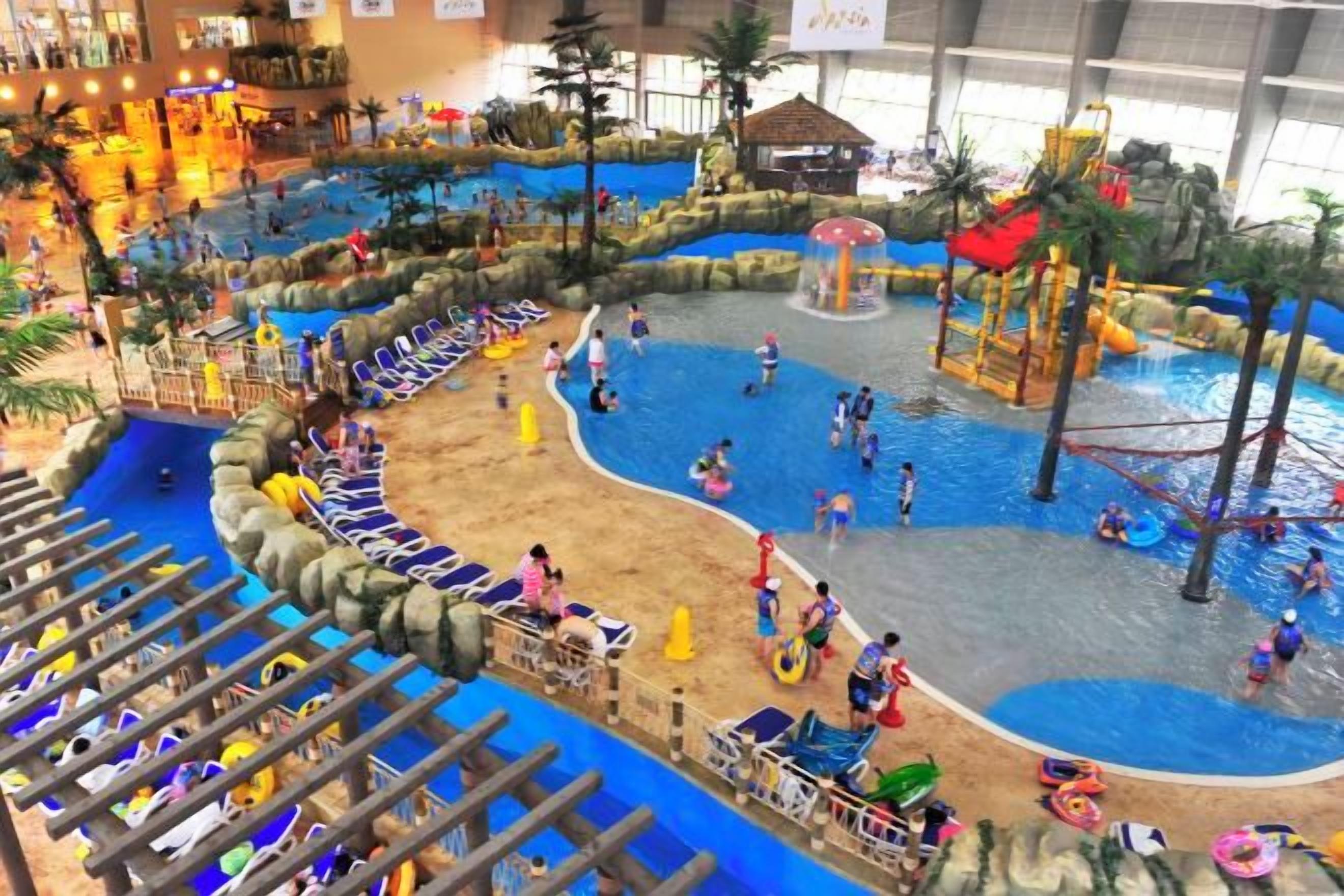Parque acuático interior con toboganes, piscinas y una zona de juegos.