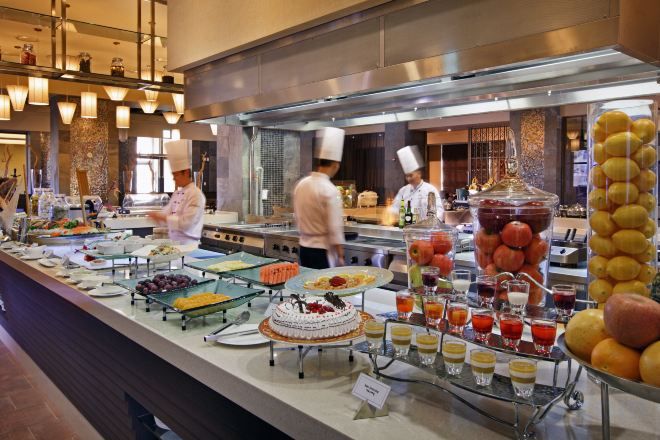 A buffet with various food items and a chef in the background.