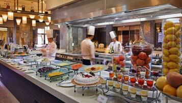 A buffet with various food items and a chef in the background.