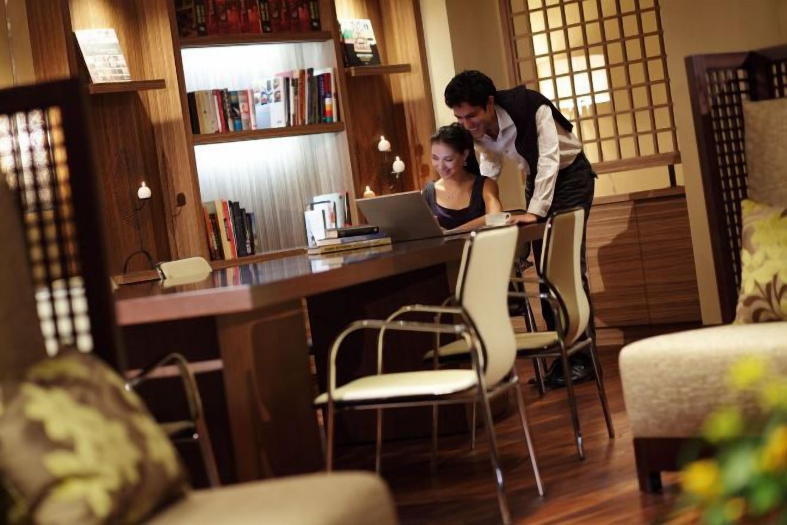 A room with a wooden desk, chairs, a bookshelf, and a laptop.