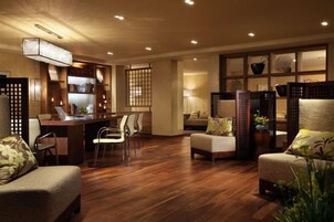 Un salón amplio con suelo de madera, un escritorio con ordenador y varios asientos.