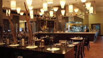 A restaurant interior with a bar area, dining tables, chairs, and pendant lighting.