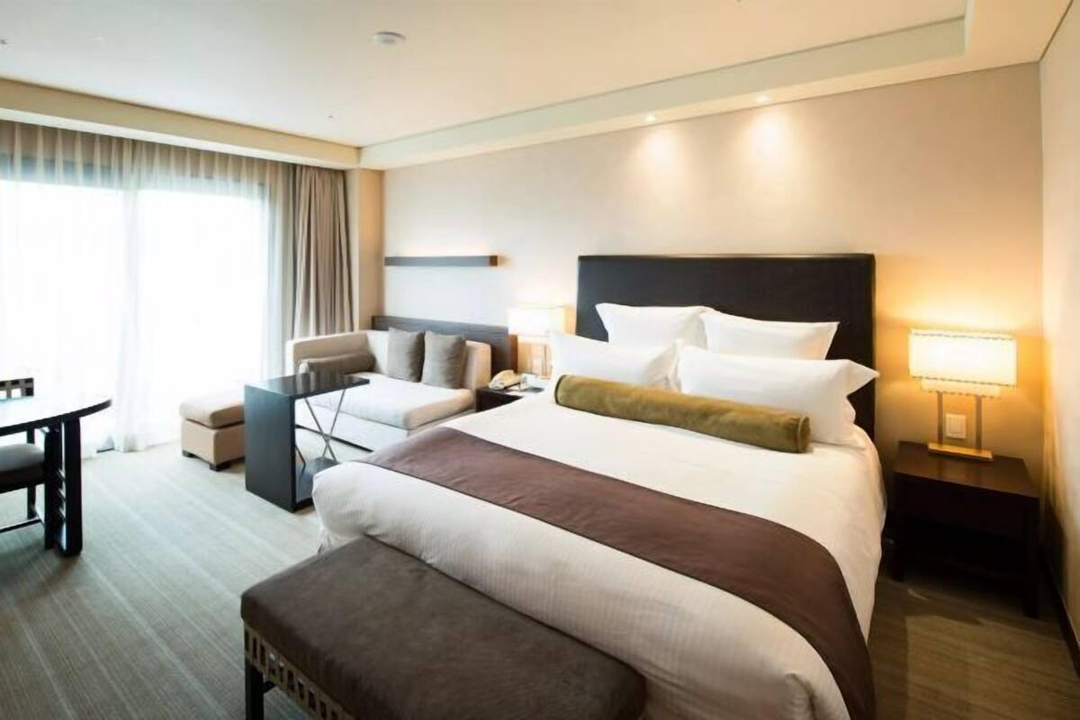 Ein Hotelzimmer mit einem großen Bett, einem Schreibtisch, einem Sessel und einer Couch.