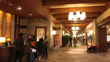 A hotel lobby with a reception desk, a chandelier, and a corridor with a tiled floor.