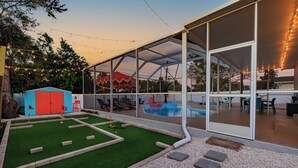 A covered outdoor area with a pool, artificial grass, and a small shed. - Pickleball court, heated pool, mins to the beach, game room & tons of amenities. (Largo)