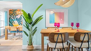 A dining area with a wooden table, wicker chairs, and a large plant. - Pickleball court, heated pool, mins to the beach, game room & tons of amenities. (Largo)