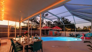 A covered outdoor area with a pool, lounge chairs, and a dining table with chairs. - Pickleball court, heated pool, mins to the beach, game room & tons of amenities. (Largo)