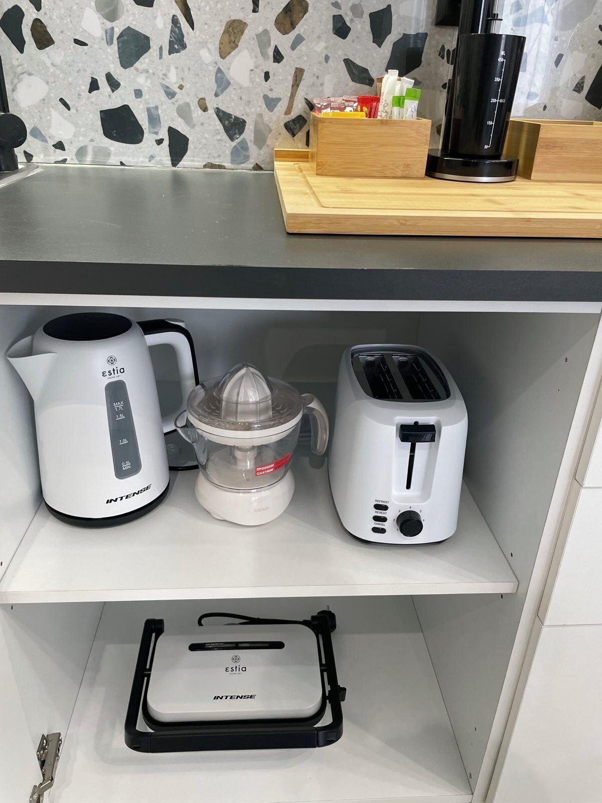 Une étagère de cuisine avec une machine à café, un extracteur de jus et un grille-pain.