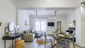 Un salon moderne comprenant un canapé, une table à manger avec des chaises, un téléviseur et un coin cuisine.