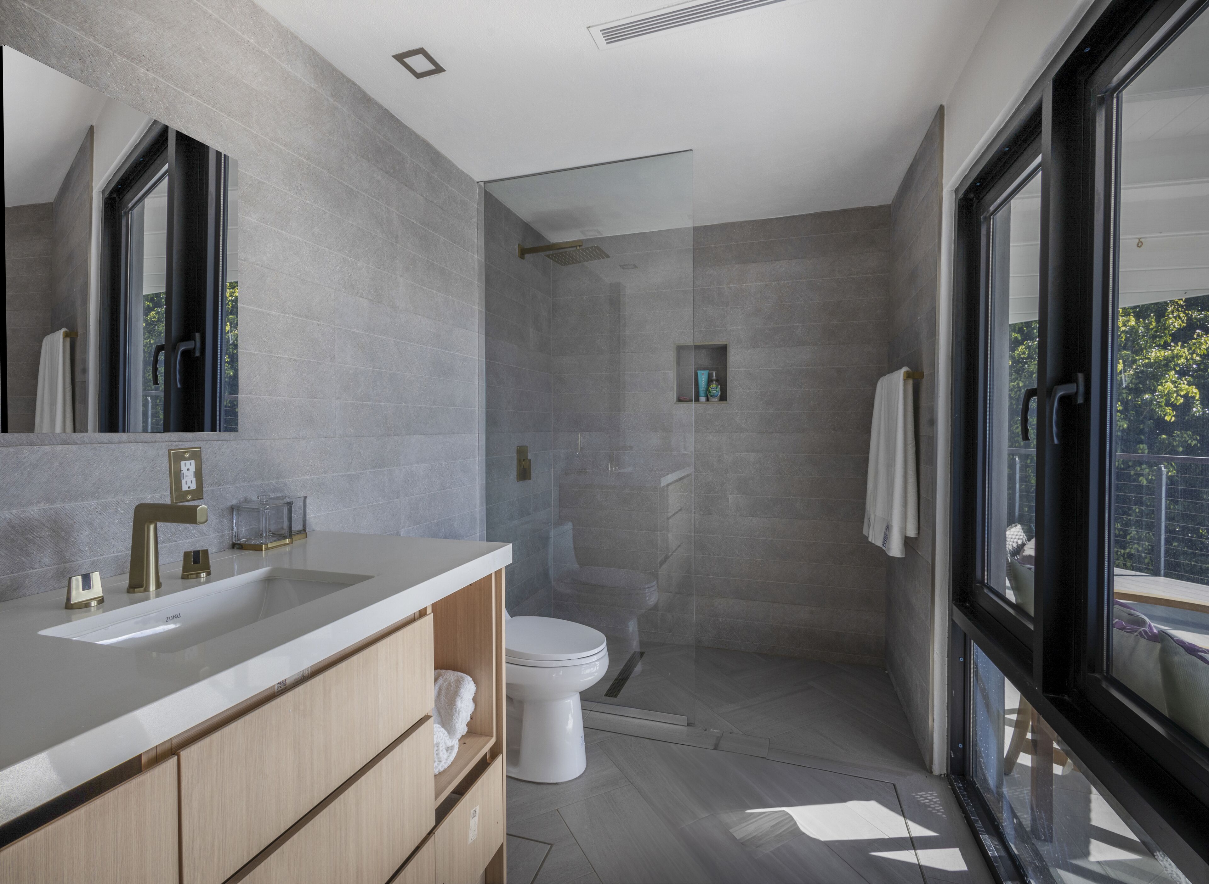 Een moderne badkamer met een grote spiegel, dubbele wastafels, een toilet en een douchecabine.