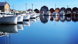 A marina with several boats docked, a building with a sloped roof, and a clear blue sky. - Country cottage, exceptional view, lake, dunes and sea. 5 minutes from the beach (Kensington)