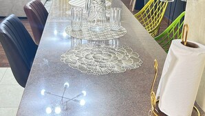 Un espace repas avec une longue table, dressée avec de la verrerie et agrémentée d’un centre de table décoratif.