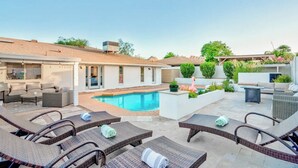 A poolside area with lounge chairs, a swimming pool, and a patio with outdoor furniture.