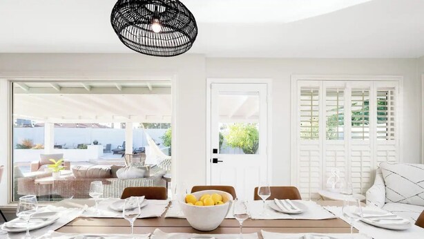 A dining area with a table set for four, a bowl of lemons, and a view of the outdoors.