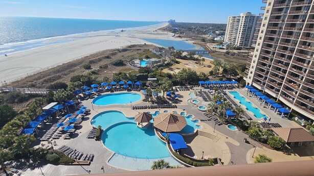 Een resort met meerdere zwembaden, toegang tot het strand en hoge gebouwen.